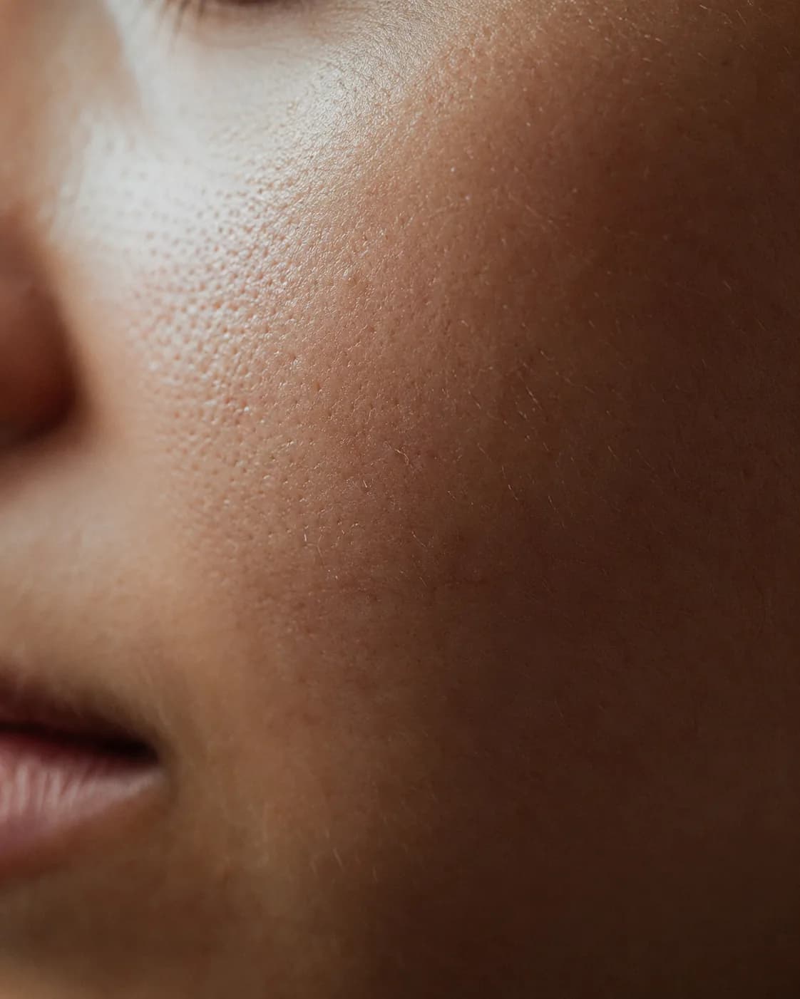 Soft, even editorial skin photography on a warm ground.